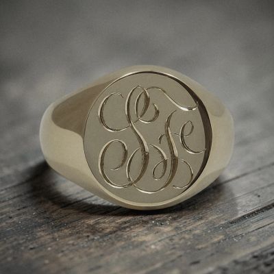 Elegant gold signet ring with intricate engraved initials.