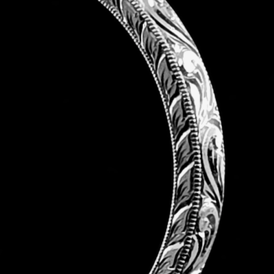 Close-up of an intricately designed silver bracelet against a black background.