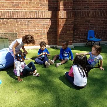 Students in play yard sitting and re-grouping and playing.