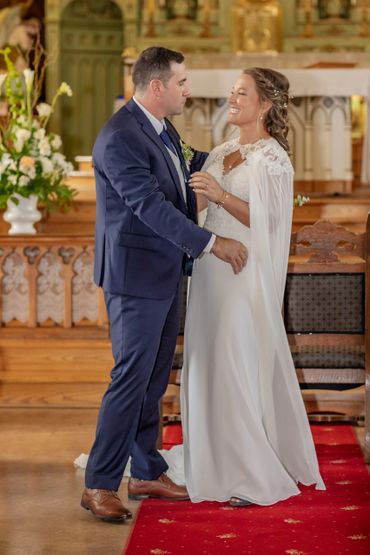 A bride and groom share a joyful moment during their wedding ceremony in a church.
