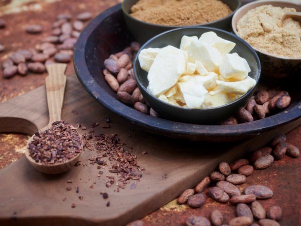 A bowl of ingredients for making chocolate bars including cocoa butter, panela and oat milk powder