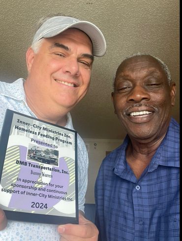 Two men smiling, one holding a plaque for Inner-City Ministries support.