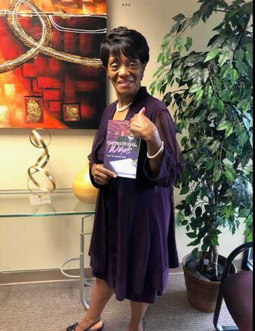 Woman in purple dress holding a book titled 'Inspirational Words'.