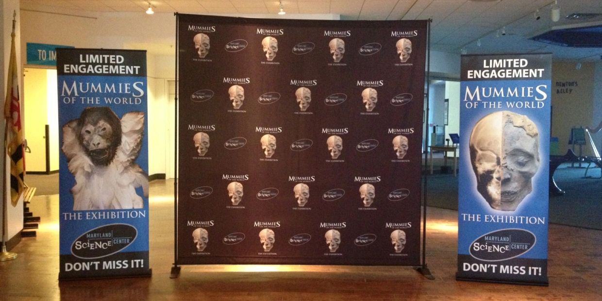 Two banners and a backdrop for the "Mummies of the World" exhibition.