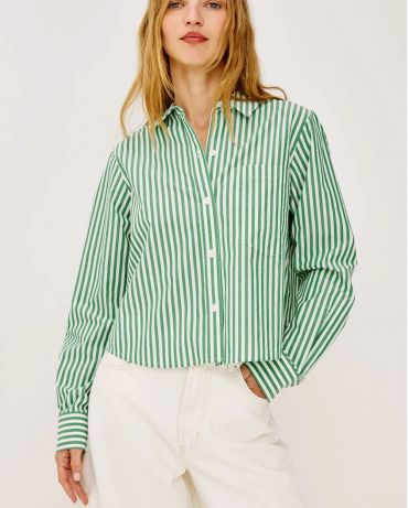 Woman wearing a green and white striped shirt with white pants.