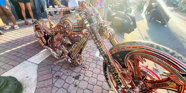 Intricately designed custom motorcycle with vibrant red and gold details on a city sidewalk.