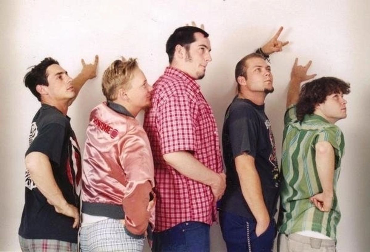 Five men standing in a line making rock hand signs.