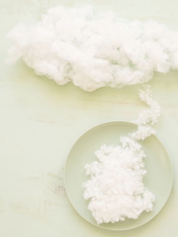 Fluffy cotton resembling clouds on a plate with a trail connecting them.