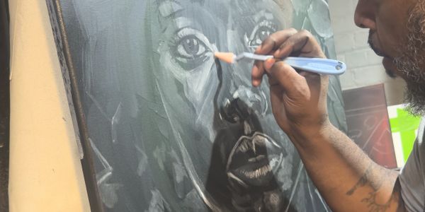 Artist painting a detailed black and white portrait on canvas.
