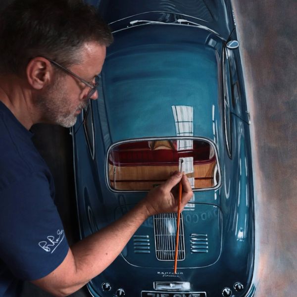 Man painting a highly detailed vintage car model with precision.