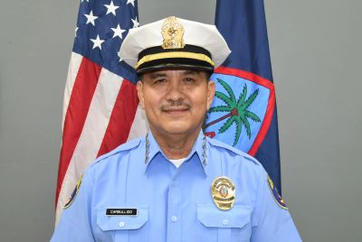 Uniformed officer standing in front of flags.