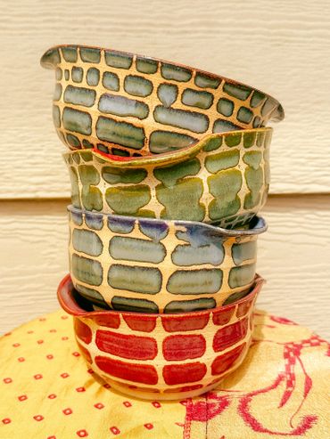 Stacked ceramic bowls with colorful geometric patterns on a cloth.