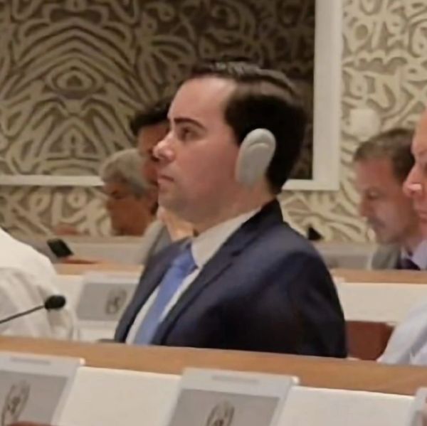 Man in a suit wearing headphones in a conference setting.
