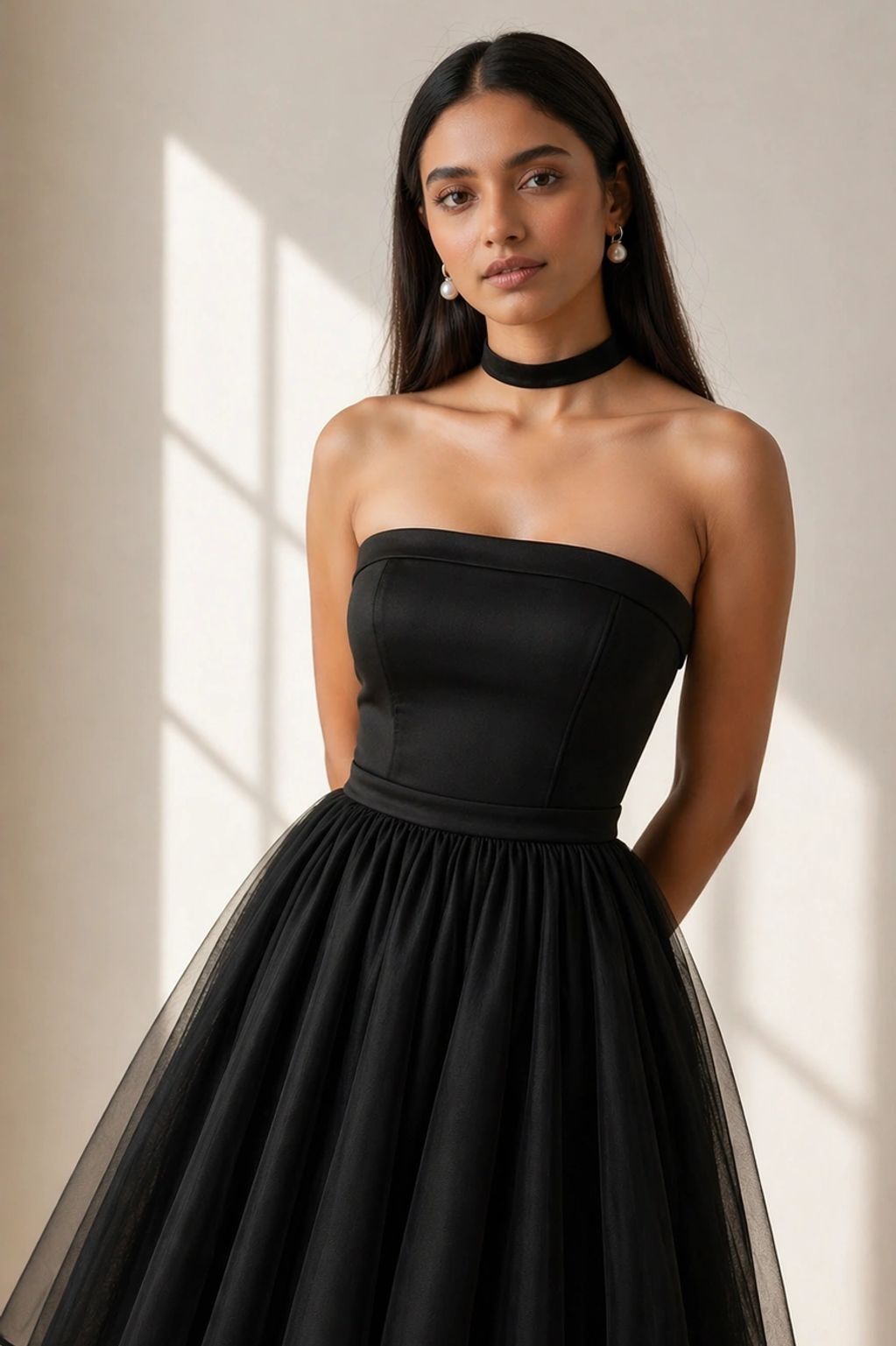 Elegant woman in a strapless black dress with pearl earrings and choker.