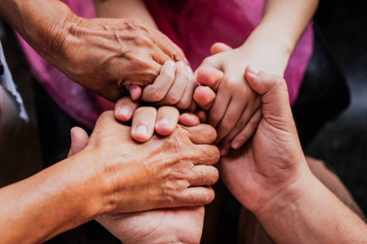 Close up of a family holding hands in unity standing strong against generational cycle of abuse. 
