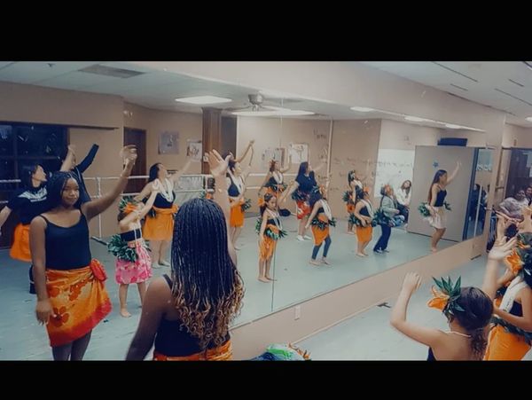 Group of young girls practicing a traditional dance in a studio with mirrors.