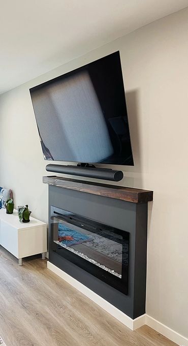 Dark grey fireplace, modern style, black flat screen TV on the wall on top of it