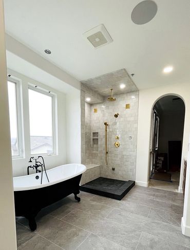 Bathroom remodeled by Top Line Remodeling Inc. Black separate tub, tiled shower, arched entrance