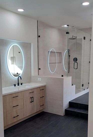 brown vanity, oval mirrors, black stairs leading to the shower