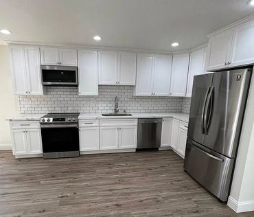 photo of the kitchen with white cabinets, grey hardwood floors