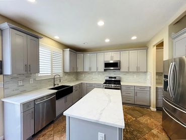 photo of the kitchen with white marble kitchen island, stove, black sink