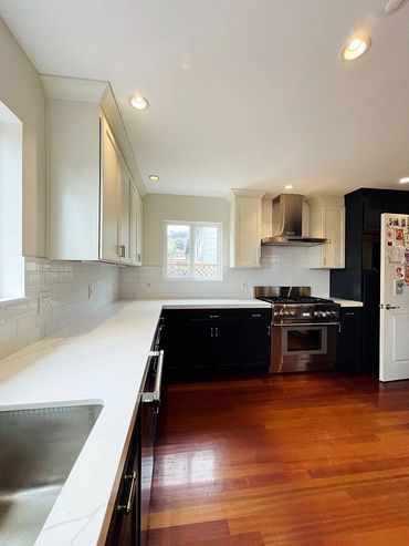 kitchen renovation photograph, steel sink, white counter, black cabinets, stove, brown floors