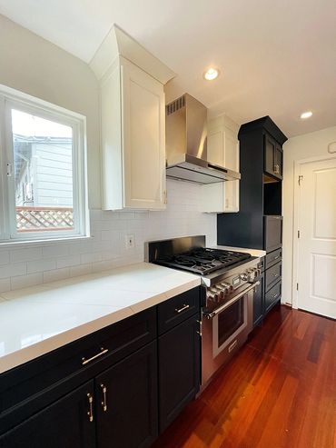 stove, black cabinets, white kitchen counter