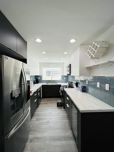  narrow kitchen with blue wall tiles and black cabinets