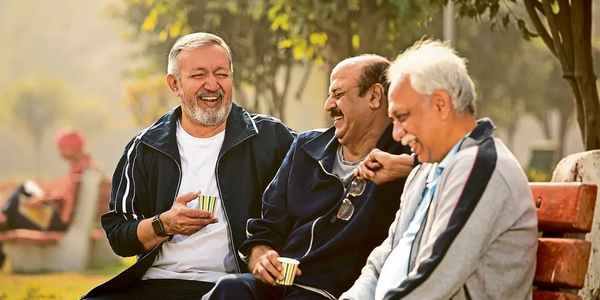 Group of seniors sitting on bench laughing together