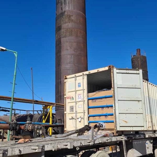 Industrial site with a shipping container and large pipes.