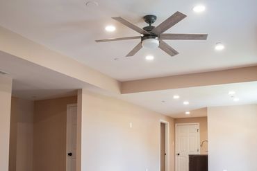 Empty room with beige walls, wooden floor, and ceiling fan.