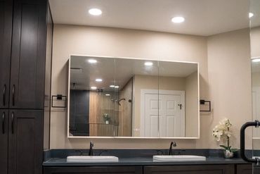 Modern bathroom with double sinks, dark wood cabinets, and a large mirror.