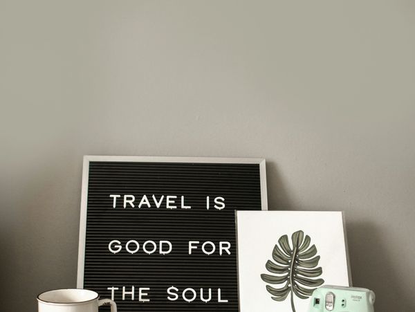 Travel-themed decor with a sign, passport, camera, sunglasses, and mug on a table.