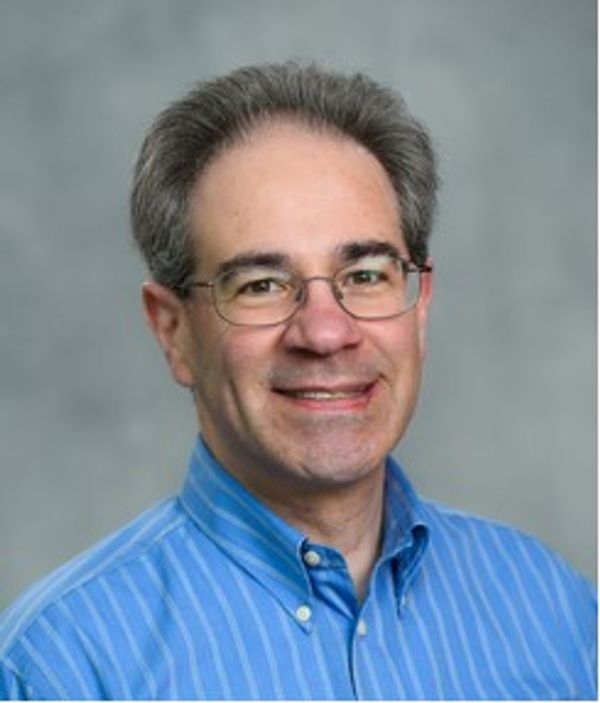 Smiling middle-aged man wearing glasses and a blue striped shirt.