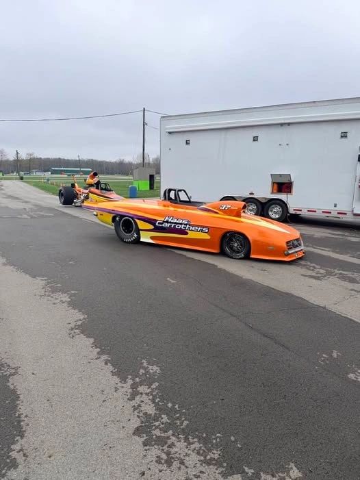 Two colorful drag racing cars parked on a race track.