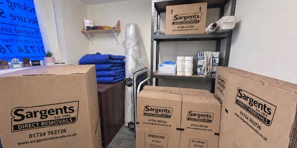 Packed cardboard boxes labeled Sargents Direct Removals in a storage room.