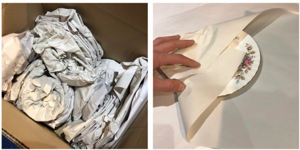 Fragile items wrapped in paper inside a cardboard box for shipping.