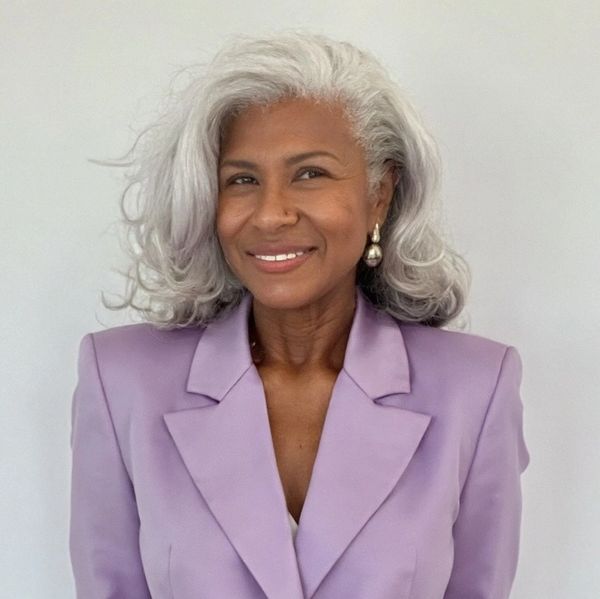 Elegant woman with silver hair wearing a lavender blazer and pearl earrings.