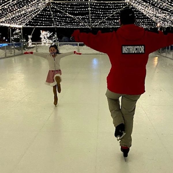 Ice skating lesson under string lights.