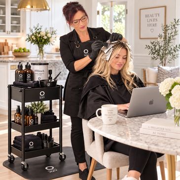 Hairdresser foiling client's hair in a cozy salon setting.