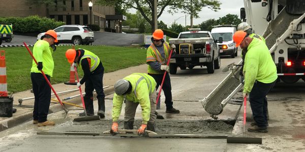 Construction workers pouring and smoothing concrete on a road.