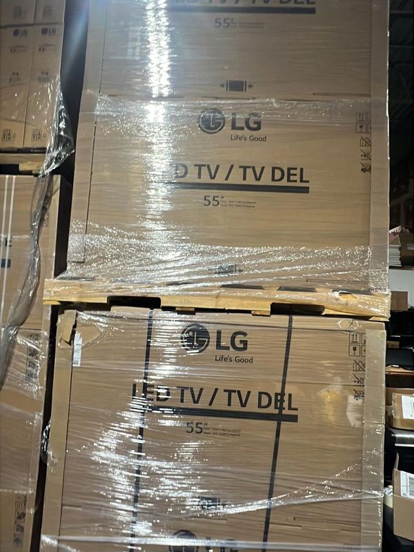 Stacked LG 55-inch LED TV boxes wrapped in plastic in a warehouse.
