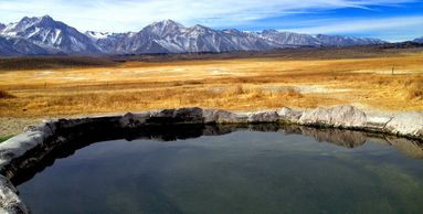Natural hot spring pool with mountain backdrop.