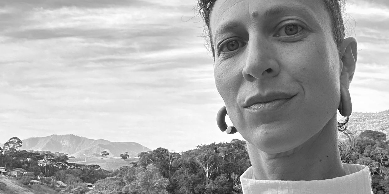 Close-up of a person outdoors with mountains in the background.