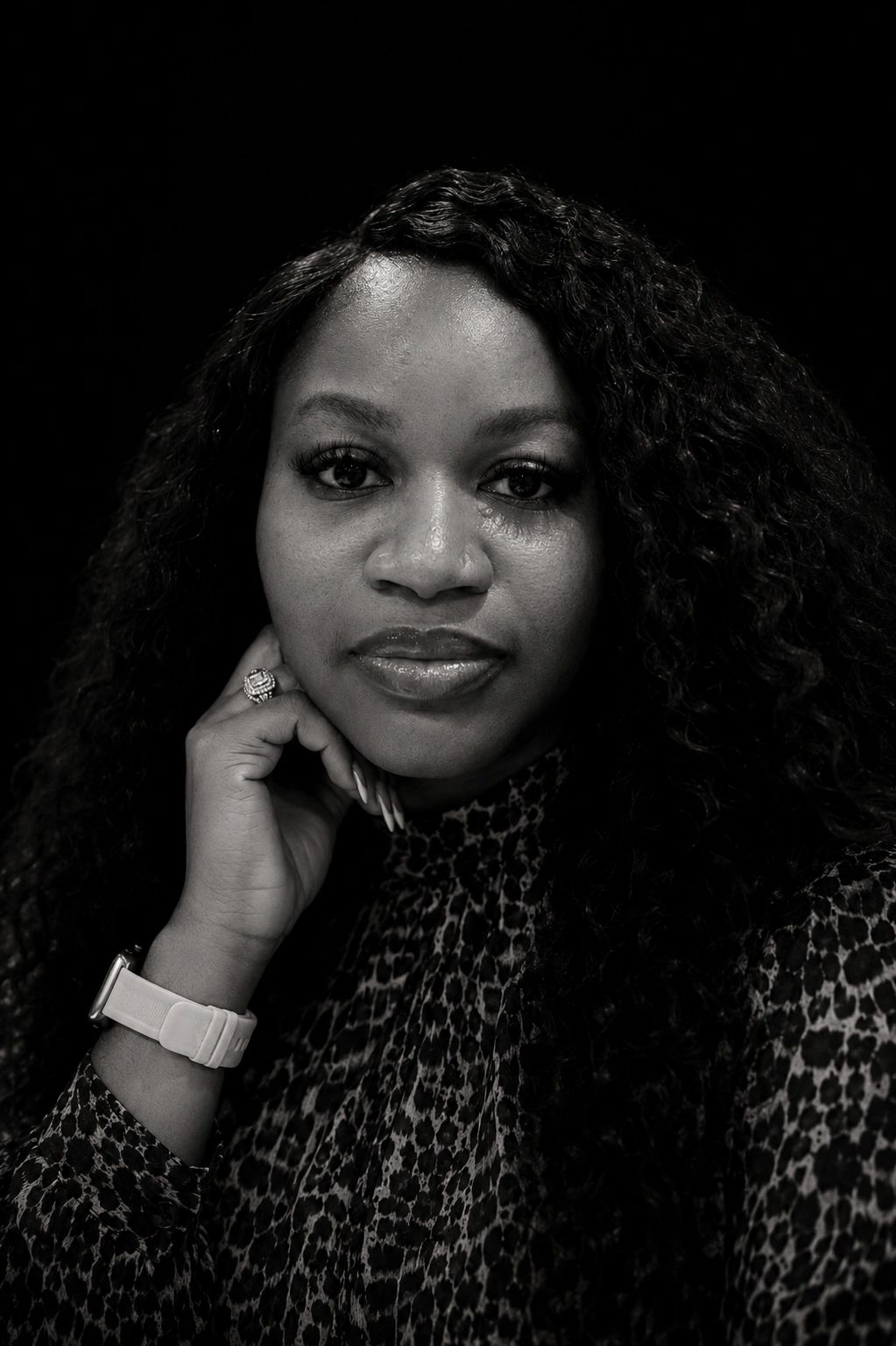 Black and white portrait of a woman with curly hair and a patterned top.