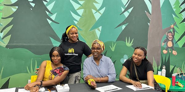 Four women smiling at an event with a forest backdrop.