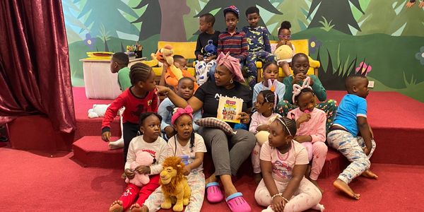 Woman reading to children in a colorful room.