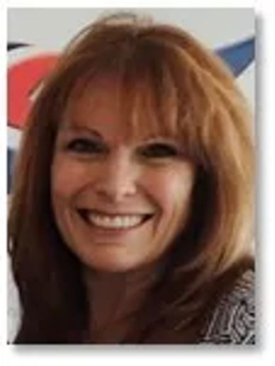 Smiling woman with red hair and bangs.