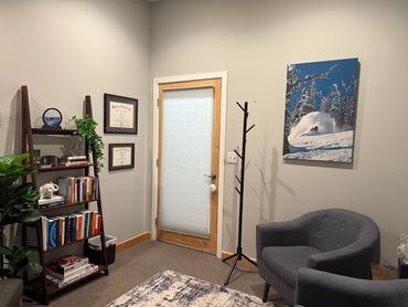View of office from inside, bookshelf, plant, door, coat rack, image of skier, chairs