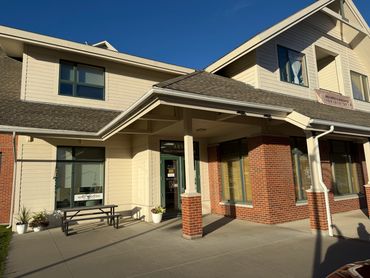 Exterior of office building, green doors, picnic table, brick walls